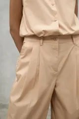 Pantalon de corte relajado y tiro alto, confeccionado en algodon, con pliegues frontales y bolsillos laterales.