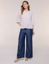 Blusa de gasa liviana blanca con estampado floral en tonos azules y rosados, escote en V, mangas 3/4 abullonadas con puños elásticos y corte fluido.