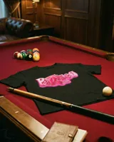 Remera negra de corte babytee con estampa frontal en tonos rosados que incluye la palabra 'Pariseo' con efecto brillante y un pequeño dibujo de labios.