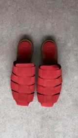 Zuecos de punta cuadrada, confeccionados en gamuza de color rojo, con diseño de tiras anchas entrelazadas y plantilla marrón con detalle grabado.