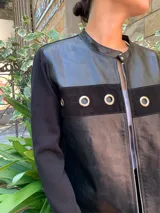 Campera negra con frente de cuero, mangas largas de tejido de punto y cierre frontal con cremallera.
