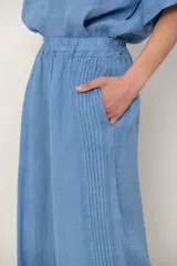 Pantalón palazzo de lino color blanco, con cintura elástica fruncida, bolsillos laterales y detalle de alforzas verticales en los laterales.