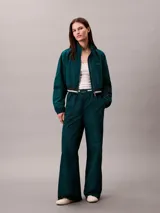 Pantalón deportivo Calvin Klein de pierna ancha y tiro medio, confeccionado en tafetán color verde oscuro. Posee cintura elástica con logo de la marca visible.