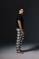 Pantalon de pijama con estampado de cuadros en tonos blanco, negro y gris, con cintura elástica y cordón ajustable.