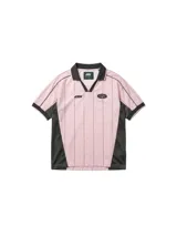 Camiseta de estilo deportivo con cuello polo, confeccionada en tela técnica de secado rápido. Presenta un diseño a rayas verticales en color rosa con paneles laterales en malla negra, mangas cortas con bordes negros y detalles gráficos estampados en el frente.