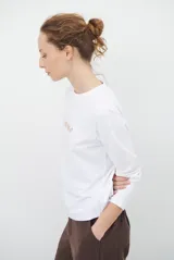 Remera de manga larga color blanco, con cuello redondo y diseño de bordado lineal en el centro del pecho que representa elementos de desayuno.
