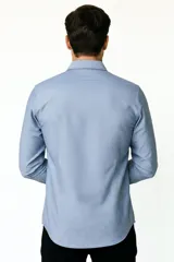 Camisa blanca de algodón, de diseño holgado y manga larga, con cuello camisero y cierre frontal de botones.