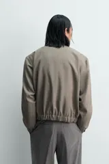 Cazadora de corte relajado confeccionada en tejido con lana, con diseño de pata de gallo en tonos marrones. Presenta cuello subido con cierre de botones, bolsillos laterales de vivo y acabados elásticos en puños y bajo.