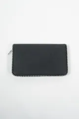 Billetera rectangular color negro con textura granulada, cierre perimetral y borde decorado con tachas metálicas plateadas.