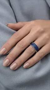 Anillo de plata 925 con diseño de banda ancha, engastado con múltiples circonias azules en un patrón geométrico entrelazado.