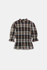 Blusa de cuello subido con diseño de cuadros en tonos marrones, negros y blancos. Presenta mangas cortas con terminación en volantes y un corte ajustado con detalle de volado en la cintura.