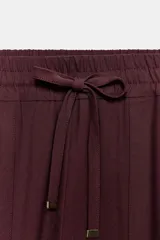 Pantalón jogger de tiro medio, color bordó, con cintura elástica ajustable mediante cordones, bolsillos delanteros y puños elásticos en los tobillos.