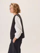 Chaleco de tejido de punto con textura en relieve, color beige, con cierre frontal y bolsillos laterales. Diseño sin mangas con cuello redondo.