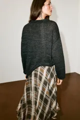 Jersey de punto color negro con cuello redondo y manga larga, de diseño amplio y bajo asimétrico.