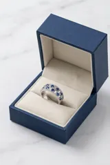 Anillo de plata 925 con diseño de banda ancha, decorado con una hilera central de circonias blancas en corte baguette y dos hileras laterales de circonias azules redondas.