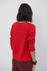 Remera de manga larga en color azul marino, confeccionada en tejido suave. Presenta un delicado detalle de bordado festoneado en color blanco tanto en el cuello redondo como en los puños, aportando un toque distintivo a esta prenda básica.