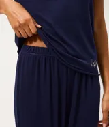 Pijama de dos piezas compuesto por una blusa de manga corta con escote redondo y un pantalón largo de corte recto con cintura elástica. La prenda presenta un bordado sutil en el pecho y un acabado liso.