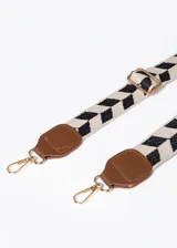 Cartera marrón de cuero sintético con tres compartimentos, cierre y correa con estampado geométrico en blanco y negro.