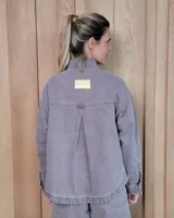 Sobrecamisa de denim con diseño de rayas verticales en tonos azules. Presenta cuello clásico, cierre frontal con botones y bolsillos delanteros de parche.