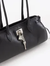 Cartera Kate de cuero vacuno diseñada para llevar al hombro, con cierre principal y bolsillo interno. Presenta aplique de candado y llavero tipo birkin en el frente, además de tiras laterales decorativas.