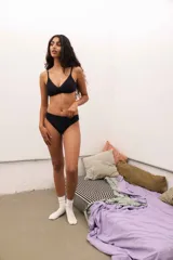 Pantie less de encaje negro, corte bajo y tiro bajo, con detalle de encaje en los bordes.