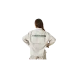 Camisa de manga larga Eme Studios modelo Evo Pirouette, de color beige con diseño de rayas verticales finas. Presenta un bolsillo aplicado en el pecho con el logotipo de la marca bordado en verde oscuro, cuello camisero y cierre frontal de botones.
