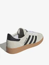 Championes Adidas Handball Spezial color crema con las tres tiras laterales en negro y suela de goma marrón.