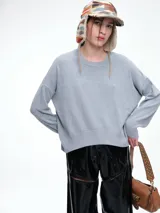 Sweater de punto color negro, con cuello redondo, hombros caídos y terminaciones acanaladas en puños y ruedo. Presenta un diseño de calce relajado y tejido suave.