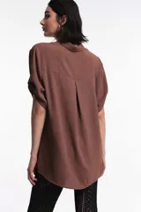 Camisa blanca de manga corta con puños doblados, cuello clásico y cierre frontal de botones.