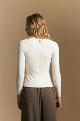 Polera de punto acanalado color gris, con cuello alto y mangas largas, de calce ajustado al cuerpo.