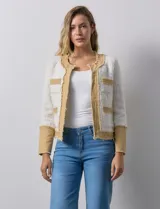 Chaqueta Nanette de tejido tweed y denim color blanco con cuello a la base y abertura central. Delantera con bolsillos, puño con aplique de botones metálicos y terminación desflecada.