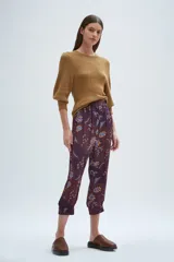Babucha de corte relajado, con cintura elástica fruncida y puños anchos en el ruedo. Presenta un diseño estampado con motivos florales y botánicos en tonos bordó, azul y amarillo.