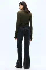 Jeans de denim negro con leve stretch, tiro bajo, corte ajustado hasta el muslo y acampanado desde la rodilla. Presenta cierre con botones en pretina prolongada y bolsillos delanteros y traseros.