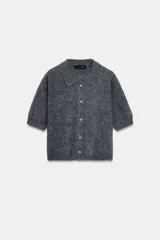 Chaqueta de punto con textura cepillada, cuello polo y manga corta. Presenta cierre frontal con botones y diseño de corte recto.