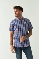 Camisa de manga corta con estampado de cuadros vichy en azul y blanco. Presenta cuello con botones, cierre frontal con botones y logo bordado en el pecho.