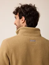 Campera de polar tipo sherpa en color azul, con cierre frontal completo, cuello alto y bolsillos laterales. Presenta un pequeño logo bordado en el pecho.