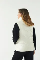 Chaleco puffer color crema con textura acolchada y bolsillos con cierre.