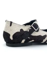 Zapato Mary Jane con estampado de vaca en blanco y negro, con correa al tobillo y hebilla plateada.