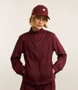 Campera rompevientos deportiva de mujer, marca Get Over, color beige con sutiles rayas verticales, cuello alto, cierre frontal con cremallera y puños ajustados.