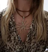 Colgante de alpaca con diseño geométrico y orgánico en forma de sol o coral, suspendido de una doble tira de cuero marrón.