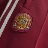 Pantalón deportivo Adidas de la selección española de fútbol, color bordó con las icónicas tres tiras blancas laterales y logo del trébol en la pierna. Presenta cintura elástica y escudo de la federación en el frente.