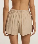 Short de playa color beige, confeccionado en viscosa y poliamida, con diseño holgado, bolsillos laterales, cintura elástica con cordón de ajuste tipo lazo y detalle de botones frontales.