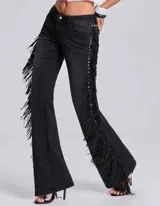 Pantalón de jean negro de corte acampanado, con detalle de flecos largos a lo largo de las costuras laterales y ojales metálicos decorativos.