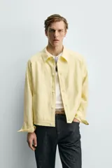 Sobrecamisa relaxed fit de color amarillo claro, confeccionada en tejido con mezcla de lyocell. Presenta cuello solapa, mangas largas raglán con puños abotonados, bolsillos de vivo en la cadera y cierre frontal con botonadura.