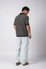 Chomba de punto con diseño de rayas verticales en color negro y blanco, cuello polo y manga corta con terminación acanalada.