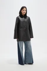 Tapado de eco-cuero negro con interior y cuello de piel sintética, cierre frontal con botones y diseño holgado.