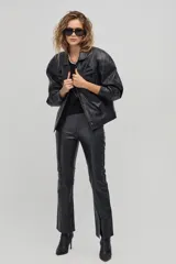 Chaqueta de cuero negro con diseño oversized, hombros estructurados y apliques geométricos en el pecho.