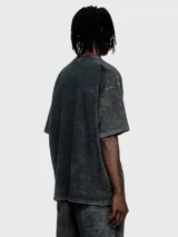 Remera Diesel de corte oversize con efecto lavado ácido en tonos oscuros. Presenta cuello redondo y un pequeño parche rectangular con el logo de la marca en el pecho.