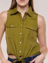 Camisa sin mangas de rayón texturado color blanco, de corte crop con cierre frontal de botones y lazos para anudar en el frente. Cuenta con cuello camisero, detalles de brillos en los hombros y bolsillos plaqué con solapa en el pecho.