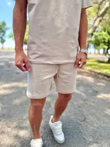 Conjunto deportivo beige compuesto por una remera de manga corta con cuello redondo y un short a juego con cordón ajustable.